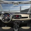 Interior view of a Fiat car featuring a dashboard, steering wheel, and scenic backdrop of the Golden Gate Bridge.