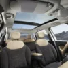 Interior view of a modern car featuring plush seats and a panoramic sunroof, showcasing a spacious and comfortable design.