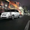 Fiat 500L in motion on a city street at night, showcasing its sleek design and modern features.