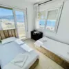 A cozy bedroom featuring two single beds, large windows with a sea view, and a modern design, ideal for relaxation and comfort.